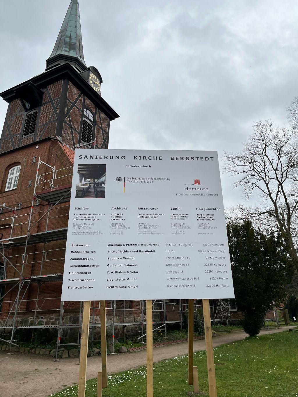 Die für die Sanierung eingerüstete Bergstedter Kirche mit dem Bauschild im Vordergrund